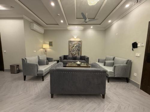 a living room with couches and chairs and a ceiling at Regency Suites in Lahore
