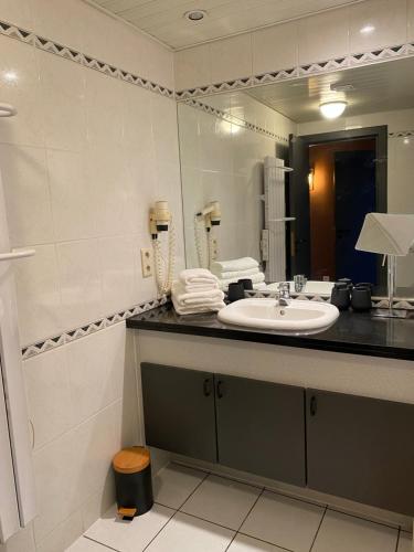 une salle de bain avec un lavabo et un grand miroir dans l'établissement Au doux Durbuy, à Durbuy