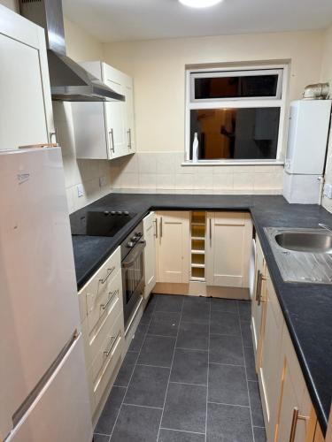a kitchen with white appliances and a black counter top at 3-Bed Home, Free Parking, Smart TV,Family & Business Ready in Slough
