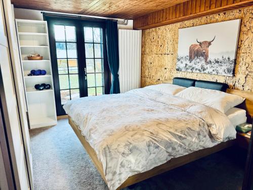 a bedroom with a bed with a picture of a cow on the wall at Résidence La Rose du Le Ours, 2 Zimmer Idyll am See in LʼAbbaye