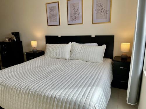 Loft con Luz Natural y Cocina Equipada في سالتيلو: غرفة نوم بها سرير أبيض كبير مع مصباحين