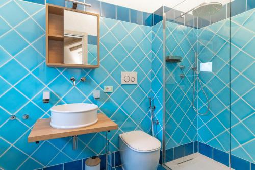 a blue tiled bathroom with a toilet and a sink at Mansion On The Hill in Olbia
