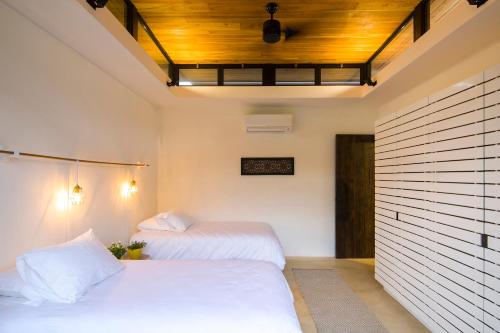 a bedroom with two beds and a wooden ceiling at Nalu Nosara Pool Villa Sol in Playa Guiones
