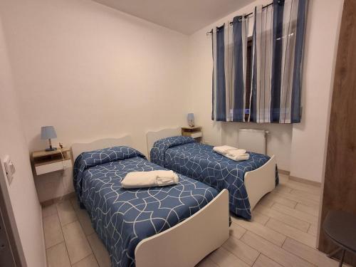 two beds in a room with blue and white sheets at Al' Rrigo in Bolsena