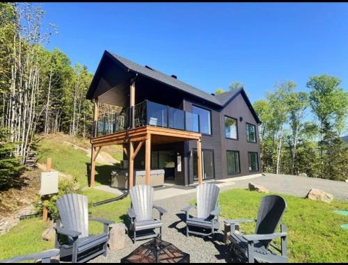 a house on a hill with chairs in front of it at Vertigo - Fleuve & Montagnes in Les Éboulements