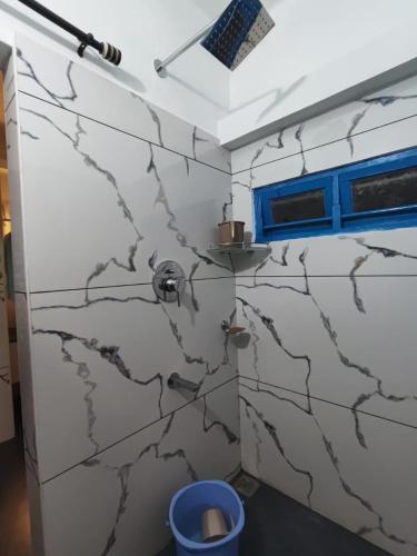 a bathroom with white marble walls and a blue window at Thiramizhi in Cochin