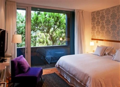 a bedroom with a bed and a large window at Hotel Casa Zapallar in Zapallar