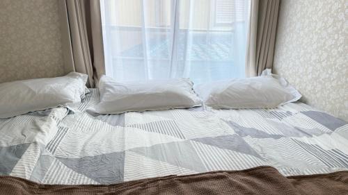 an unmade bed with two pillows and a window at aiki home in Tokyo