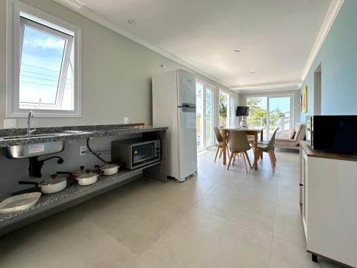 Apê Alegria - Capri Morada & Mar - Frente mar في ساو فرانسيسكو دو سول: مطبخ مع ثلاجة وطاولة مع كراسي