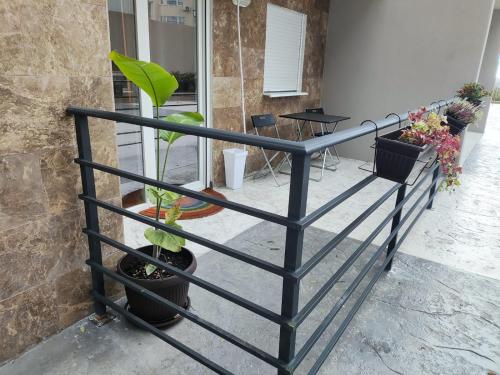 Apartments Sunny في بيشيشي: سياج أسود مع نباتات في أصص بجوار مبنى