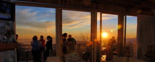 a group of people standing on a balcony watching the sunset at Casa Farellones in Farellones