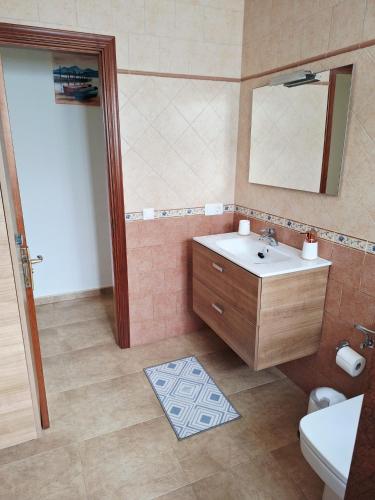 a bathroom with a sink and a mirror and a toilet at La Caracola in La Santa