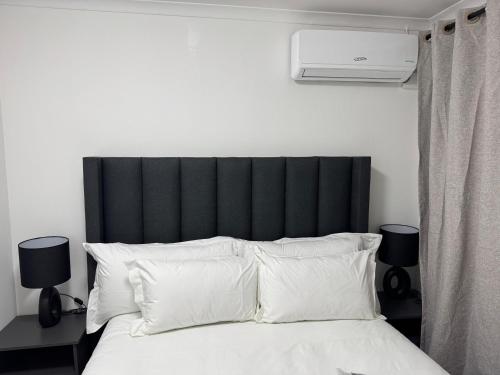 a bed with a black headboard and white pillows at Bryanston Luxury Secure 4BR Haven in Sandton