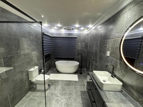 a bathroom with a toilet and a sink and a mirror at Bryanston Luxury Secure 4BR Haven in Sandton