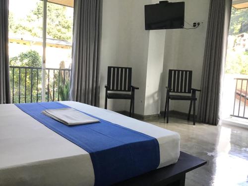 a bedroom with a bed with two chairs and a television at Everdew Kandy Rooms in Kandy