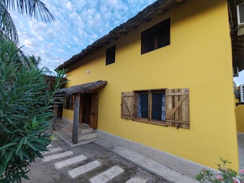 a yellow house with wooden doors and windows at Keur Teranga Nianing in Nianing