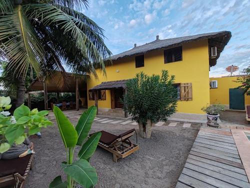 a yellow house with a patio in front of it at Keur Teranga Nianing in Nianing