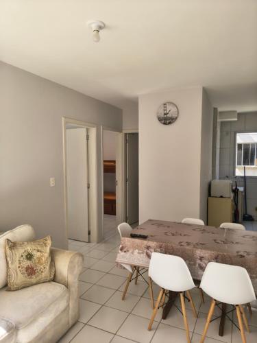 uma sala de estar com uma mesa e cadeiras brancas em Apartamento aconchegante próximo a várias praias! em Palhoça