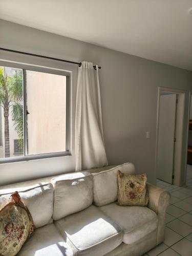 um sofá branco numa sala de estar com uma janela em Apartamento aconchegante próximo a várias praias! em Palhoça