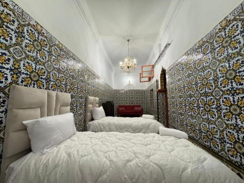 um quarto com 2 camas e uma parede coberta de azulejos em Riad Roqia em Rabat