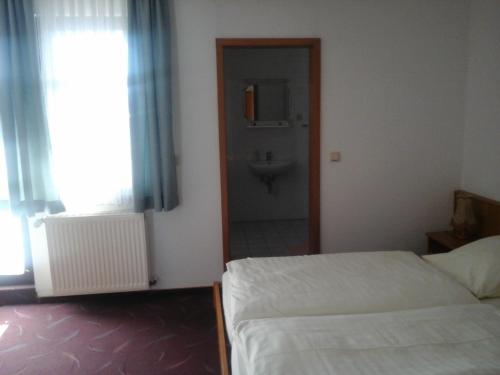 a bedroom with two beds and a bathroom with a sink at Landhotel Zur Krone in Kieselbach