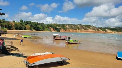 two boats on a beach with people in the water at Pousada Castelo do Gaúcho in Baía Formosa