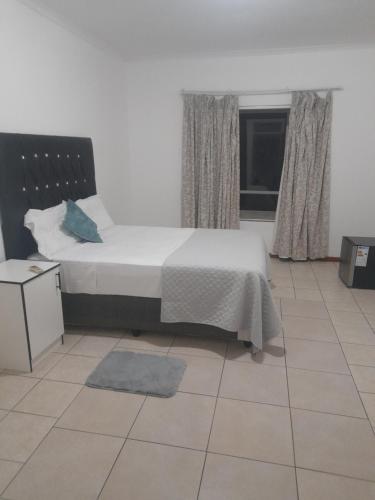 Primestay Homestead في غابورون: غرفة نوم بسرير وأرضية من البلاط