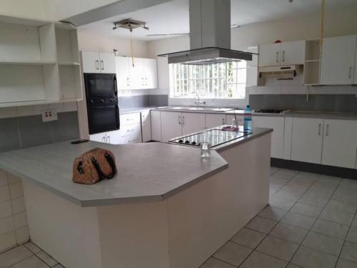 Primestay Homestead في غابورون: مطبخ بخزائن بيضاء وجزيرة مطبخ عليها قطعة خشبية