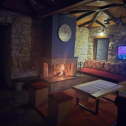 een woonkamer met een open haard en een klok aan de muur bij Κτήμα Βασίληγιάννη 
