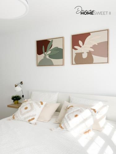 a white bed with white pillows and pictures on the wall at Oasis Dunas Sweet Family Home II Pool view by B-Rent in Corralejo