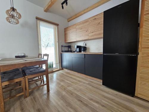 Il comprend une cuisine équipée d'une table et d'un réfrigérateur noir. dans l'établissement SierPlejs Hill - domki przy szlaku w Górach Sowich, à Sierpnica
