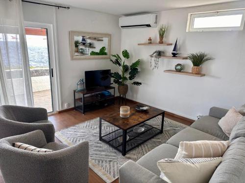 een woonkamer met een bank, stoelen en een tafel bij Casa Beira Mar in Angra do Heroísmo