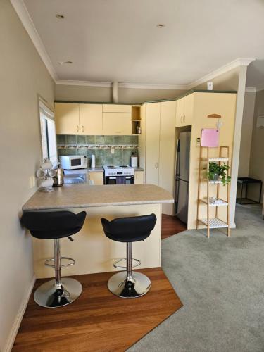 a kitchen with two bar stools in front of a counter at Ridgetop cottage in Wairakei
