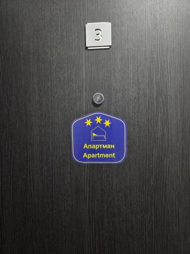 a door with a blue sign on it at Apartman Mir in Temerin