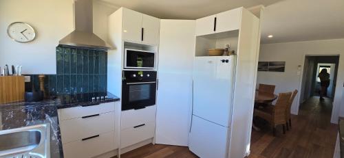 a kitchen with a white refrigerator and a table at Bumble Bee Cottage in Kerikeri