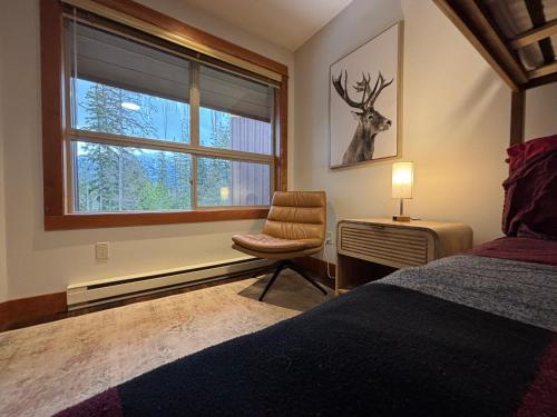 a bedroom with a bed and a chair and a window at Fully Renovated Penthouse Loft at Fernie Alpine Resort in Fernie