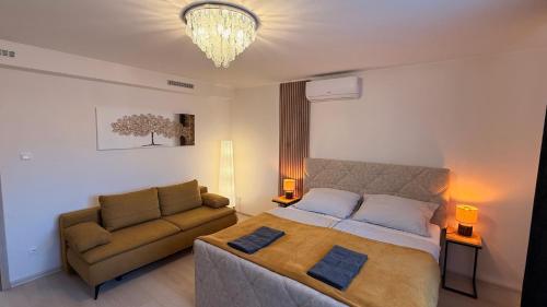 a bedroom with a bed and a couch and a chandelier at CasaBruno Vendégház Celldömölk in Celldömölk