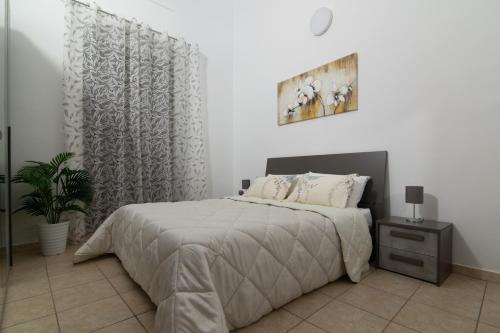 a white bedroom with a bed and a plant at Dimora Saracena in Adrano