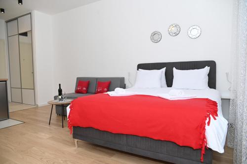 a bedroom with a large bed with red blanket at Apartman Perfect in Trebinje