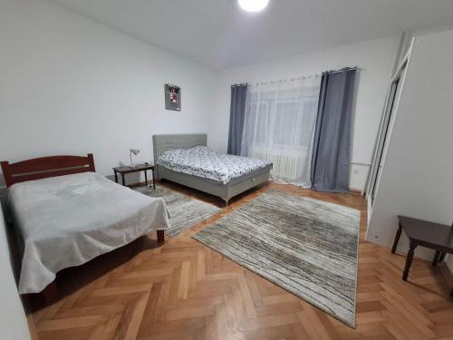 a bedroom with two beds and a rug at Paviljoni apartman in Tošin Bunar