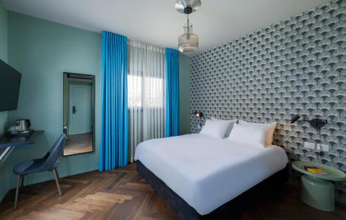 a bedroom with a white bed and a blue wall at Scarlet Hotel in Tel Aviv