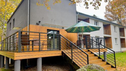 a house with a large deck with an umbrella at Apartamenty Dąbrówka Cieplice Zdrój 1,15 in Jelenia Góra