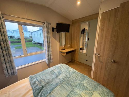 a bedroom with a bed and a window at Pine Tree Cove - your holiday retreat in Lytchett Minster