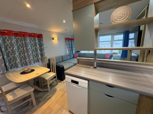 a kitchen and living room with a table and a couch at Pine Tree Cove - your holiday retreat in Lytchett Minster