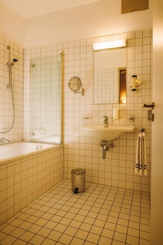 a bathroom with a tub and a shower and a sink at Hotel Vierseithof Luckenwalde in Luckenwalde