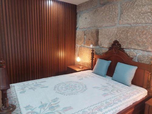 a bedroom with a bed with a stone wall at Casa Mucha - Rés do Chão e Andar in Arco de Baúlhe