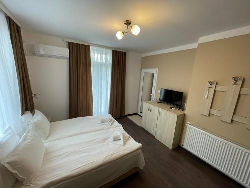 a hotel room with a white bed and a television at Къща за гости Деметра in Velingrad