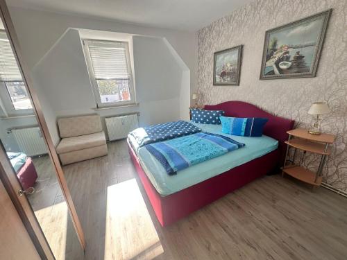 Fewo Warnemünde في روستوك: غرفة نوم بسرير احمر مع مخدات زرقاء