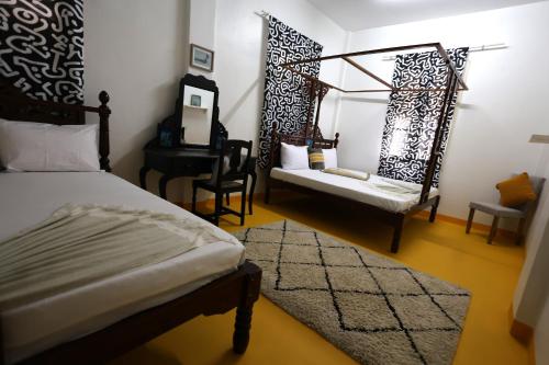 a bedroom with a bed and a chair and a desk at NOMAD Hostel Stone Town in Zanzibar City