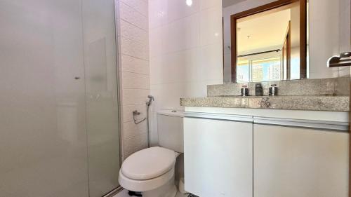 a bathroom with a toilet and a sink and a mirror at Blend - 1 Quarto 2 Camas 1 Vaga in Brasília